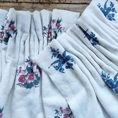 several pieces of white cloth with blue and pink flowers on them sitting on a wooden surface