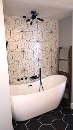 a white bath tub sitting next to a black and white tiled wall