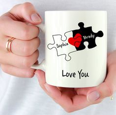 a person holding a coffee mug with two puzzle pieces on it and the words i love you