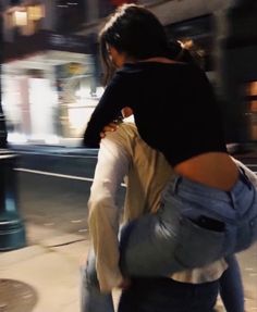 two people are walking down the street with their arms around each other and one person is carrying something behind them