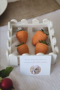 four small carrots in a carton on a table with a place for cards