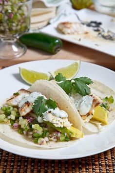 two tacos on a plate with limes and cilantro