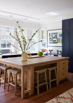 a kitchen island with stools and a potted plant on it in front of a window