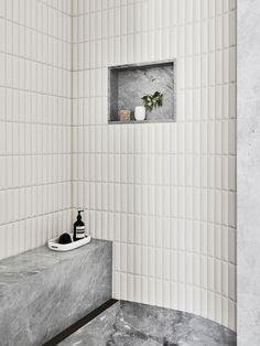 a white tiled bathroom with a shelf and soap dispenser