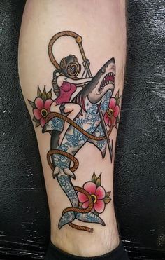 a man's leg with a shark tattoo on it and an anchor in the middle