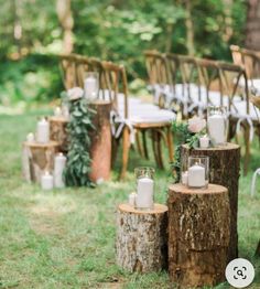 an outdoor wedding setup with candles and flowers on wooden stumps in front of chairs