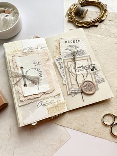 an open book sitting on top of a table next to some scissors and other items