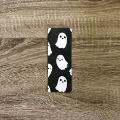 a black and white phone case with ghost faces on the front, sitting on top of a wooden surface