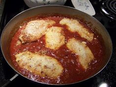 a pan filled with food sitting on top of a stove next to a pot full of sauce