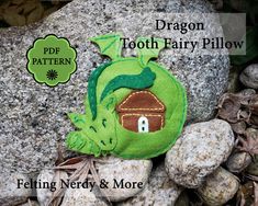 a tooth fairy pillow sitting on top of rocks next to some leaves and stones with the words dragon tooth fairy pillow below it