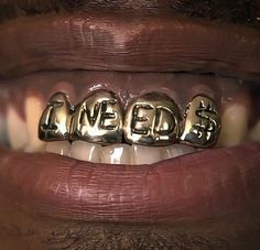 a close up of a person's mouth with gold teeth and words on it