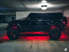 a black jeep parked in a parking garage with red lights on it's tires