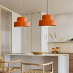 two orange pendant lights hanging over a kitchen island