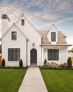 a white house with black shutters on the front door and windows in the side