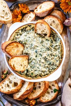 a white bowl filled with spinach dip surrounded by bread