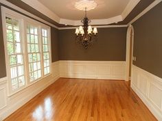 an empty room with hard wood floors and chandelier