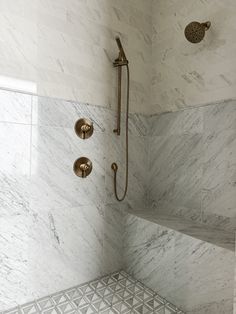 a bathroom with marble walls and flooring that has gold fixtures on the shower head