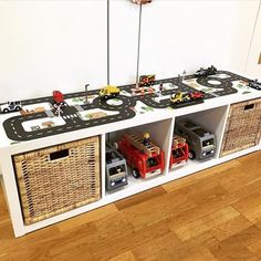 toy cars and trucks sit on top of a white shelf with wicker bins