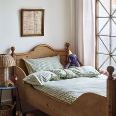 a bed with green and white checkered sheets in a bedroom next to a window