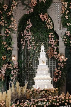 a large white cake sitting on top of a table covered in flowers and greenery