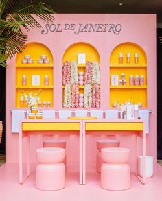 a pink and yellow table with two stools in front of it, surrounded by shelves