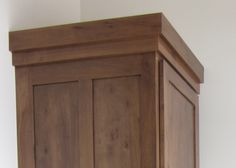 a wooden armoire in a room with white walls