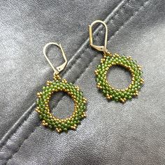 Hand Woven Green and Bronze Hoops These tiny green hoops will add a bit of sparkle to your holiday wardrobe. Deep green with just a hint of bronze to add glimmer, these little drop earrings dance with your every movement. The  lever back ear wires ensure they  remain secure no matter what your activities. The findings are lead and nickel free for your safety. Bead Weaving is a technique in which each bead is hand selected and individually stitched in place. Dimensions: Length: 1 3/4 Inches Width Nickel-free Green Beaded Earrings For Parties, Green Teardrop Beaded Earrings For Party, Green Teardrop Nickel Free Hoop Earrings, Green Teardrop Nickel-free Hoop Earrings, Nickel-free Green Teardrop Hoop Earrings, Green Beaded Hoop Earrings For Gift, Handmade Green Hoop Earrings For Party, Elegant Green Beaded Hoop Earrings, Green Hoop Earrings For Party With Ear Wire