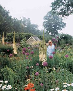 a woman standing in the middle of a flower garden