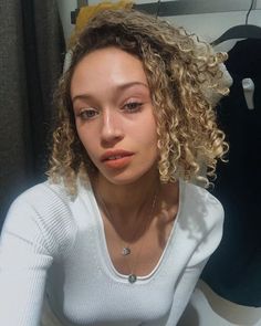 a woman with curly hair sitting in front of a mirror