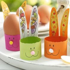 four paper easter bunnies on a plate with eggs in the background