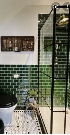 a black and white tiled bathroom with green tiles on the walls, toilet and shower