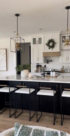 a kitchen with black cabinets and white countertops is pictured in this image, there are four stools at the center of the island