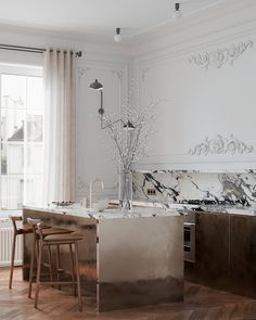 a kitchen with marble counter tops and an island in front of a window that looks out onto the street