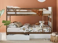 a bunk bed with two sets of mattresses and pillows on the bottom, next to a potted plant