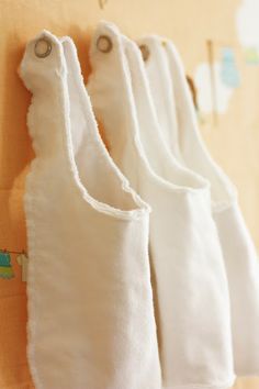 three white towels hanging on the wall in front of a wooden board with magnets