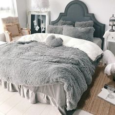 a bedroom with a large bed covered in grey blankets