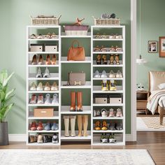 a white shelf filled with lots of shoes next to a green wall and a potted plant