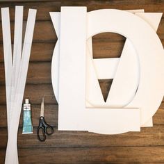 paper cutouts, scissors and glue sitting on top of a wooden table next to the letter d