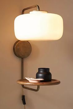 a lamp that is on top of a shelf next to a table with a vase