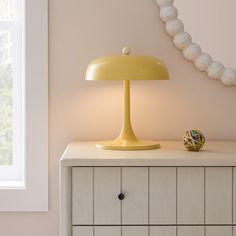 a yellow lamp sitting on top of a white dresser