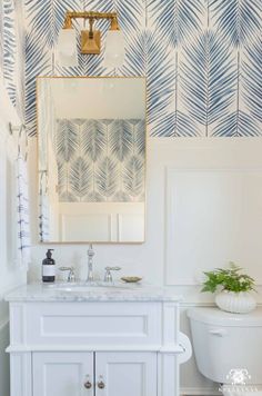 a white bathroom with blue and white wallpaper