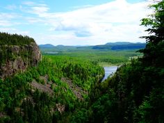 a scenic view of trees and water from the top of a hill