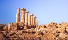 some very tall stone pillars in the middle of a rocky area with trees and bushes