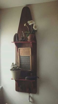 a wooden shelf with flowers and plants on it in a corner next to a window