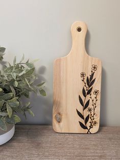 a wooden cutting board sitting next to a potted plant