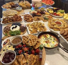 a table filled with lots of different types of food on plates and serving trays