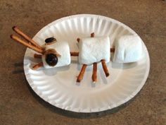 a paper plate with marshmallows and cinnamon sticks on it that have been made to look like sheep