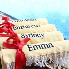 three towels with names on them sitting next to a pool