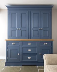 a large blue cabinet with drawers in the middle and a beige couch next to it