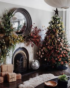 two christmas trees in front of a fireplace with presents on the mantle and other decorations